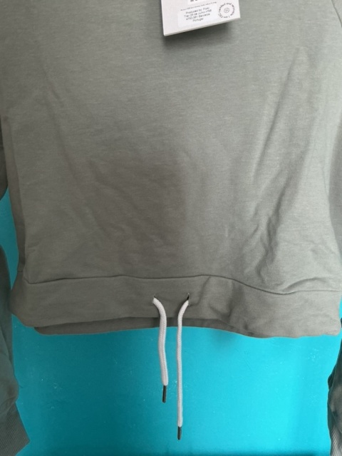 Zbliżenie na dół szarej bluzy crop ze ściągaczem i troczkami