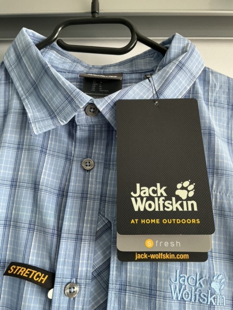 Zbliżenie na kołnierzyk i metkę koszuli Jack Wolfskin w kratę.