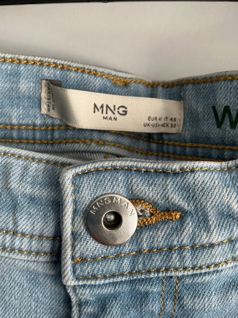 Zbliżenie na metkę Mango Man przy pasie jasnych jeansów męskich.